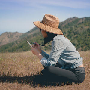 woman writing on hillside, writing from the body